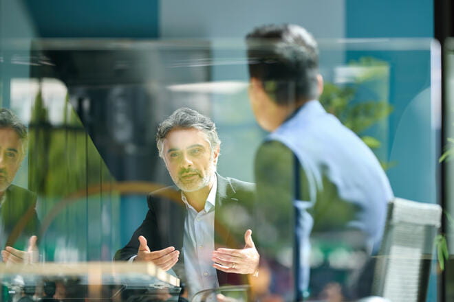 Mature businessman sitting on office balcony having meeting with colleague discussing project and gesturing, planning, togetherness, discussion