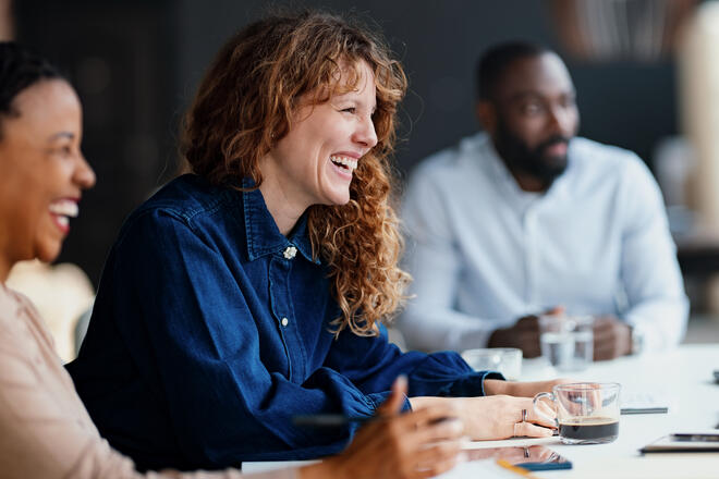 Three diverse professionals engaged in a lively discussion during a business meeting at a modern office.
