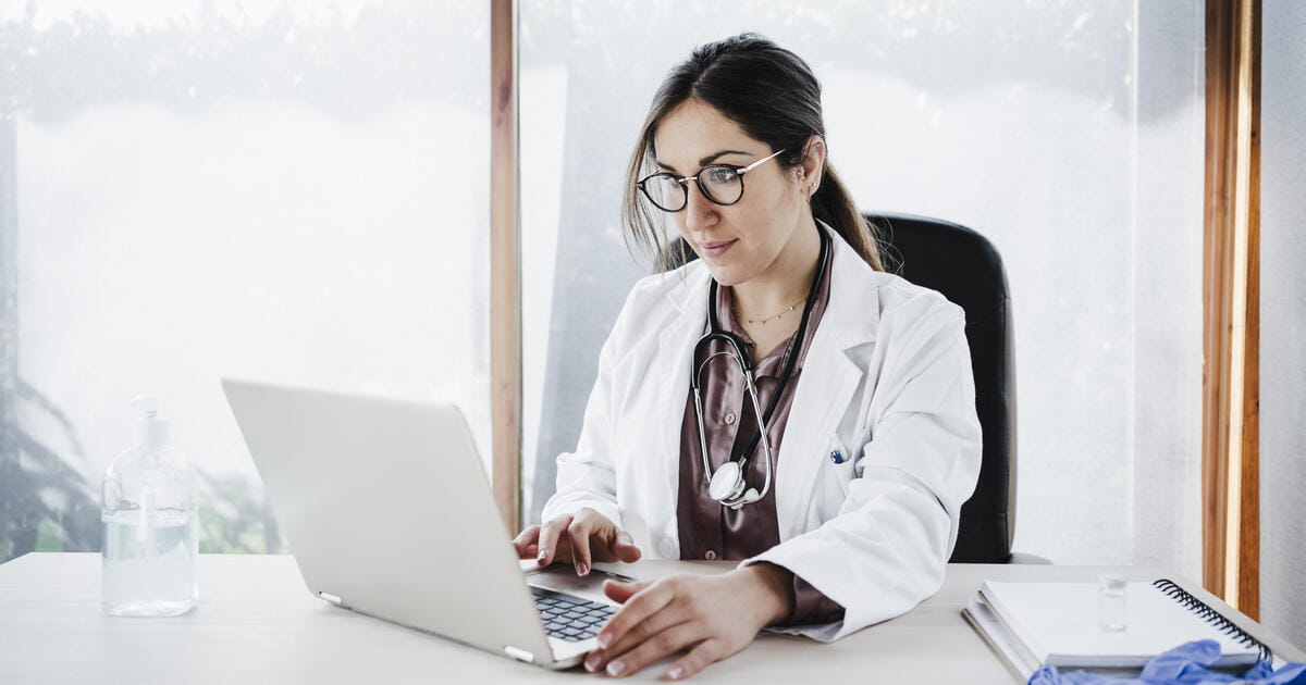 portrait of young doctor woman working in laptop in office, Madrid, Spain