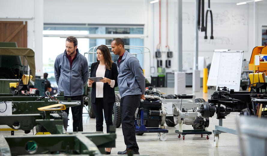 Automobile engineers and supervisor looking at incomplete vintage car.