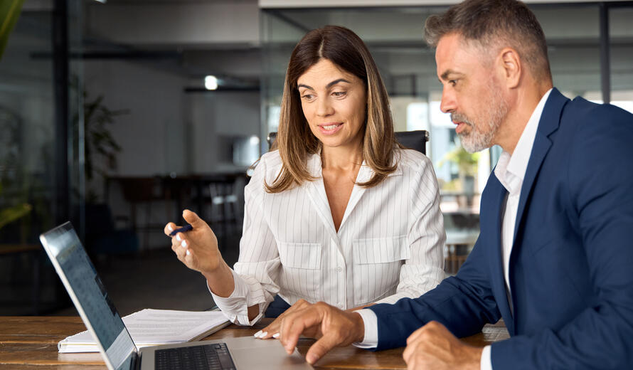  Business man mentoring business woman discussing project on laptop