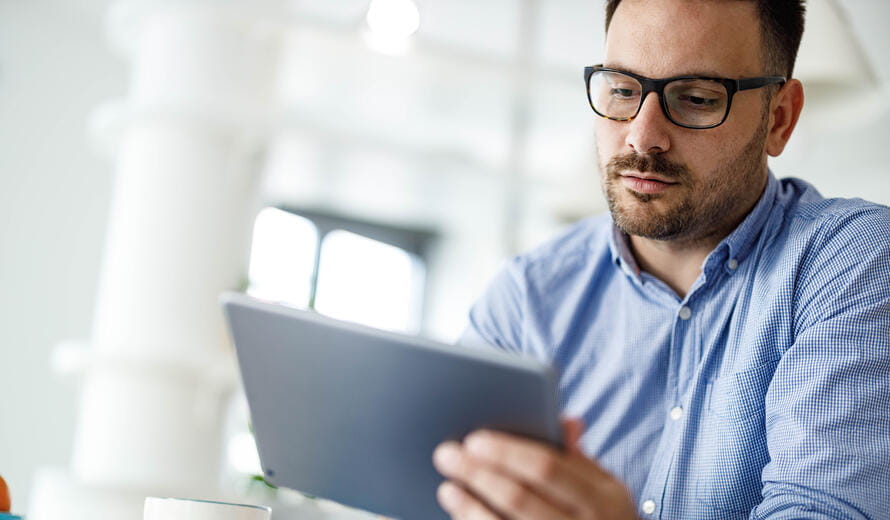 Young businessman reading an e-mail on digital tablet at home office.