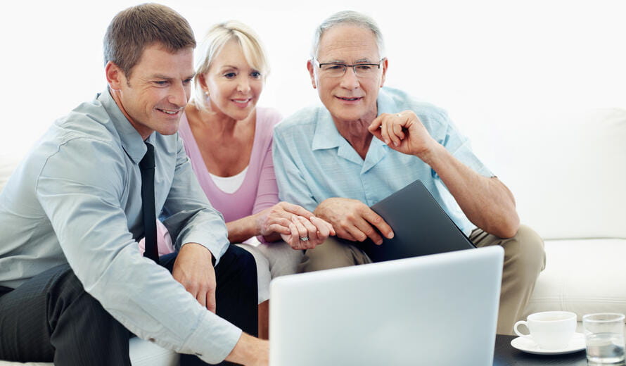 A mature couple looking at a laptop with their financial advisor.