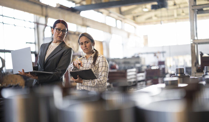 Women discuss financial project in manufacturing setting