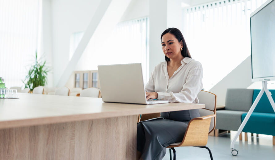 Office professional using a laptop at a meeting table.