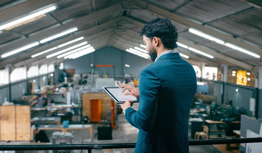 Factory manager using a tablet in a modern manufacturing facility.
