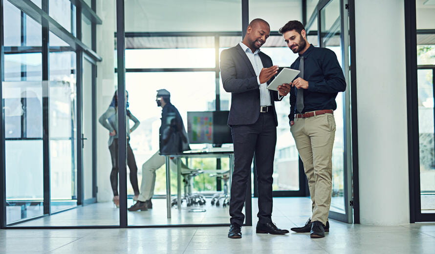 Professional image showcasing two coworkers using a digital tablet together in an office