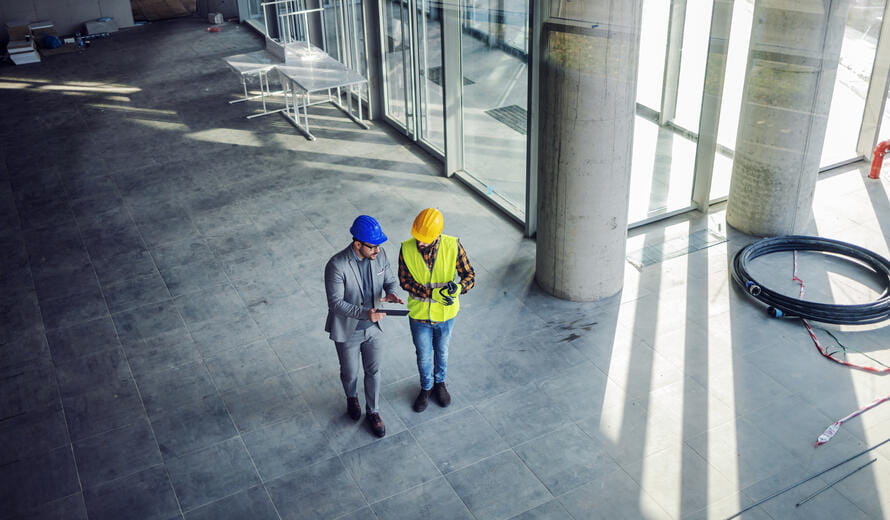 Top view of contractor and architect walking around building in construction process and talking about how they gonna build it.