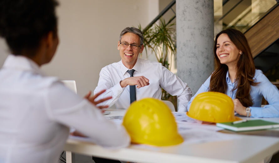 Architects engaging in a productive office meeting, discussing a new project while smiling and sharing innovative ideas, exemplifying teamwork and collaboration in a modern workspace