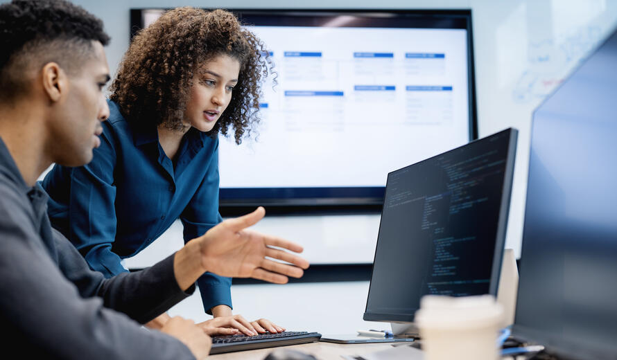 A software engineer and a female tech lead are running a test script for a web application in their startup tech office