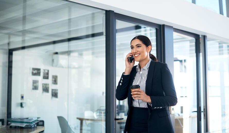 Shot of a young businesswoman walking and talking on a mobile phone in a modern office