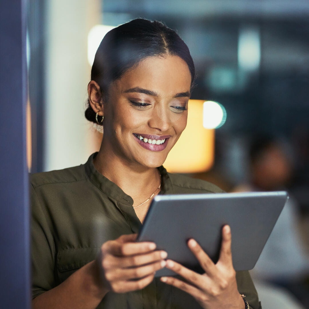 Woman smiling while looking at tablet