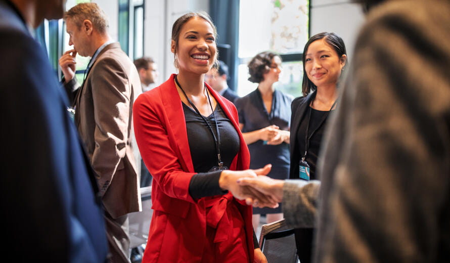 Confident businesswomen handshaking while standing in corridor of an auditorium. Female professionals greeting each other convention center.