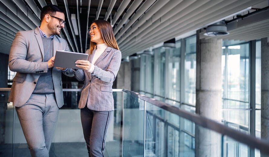 Satisfied caucasian elegant real estate agents talking about price for building in construction process thy standing in. Woman holding tablet.