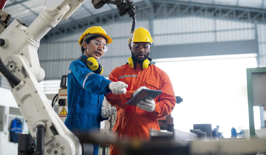 Female Quality Engineer and Male Production Engineer talking at welding robot in a factory. Cost Reduction in manufacturing process concepts.