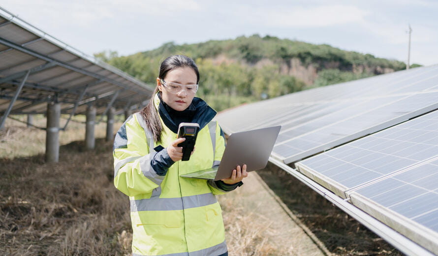 worker on a laptop near solar panels