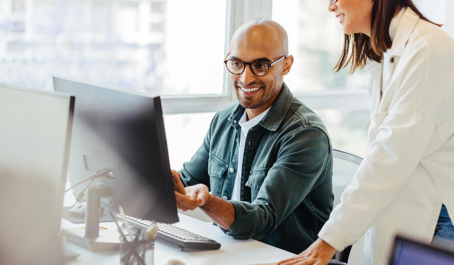 Software engineers using a computer and having a discussion in an office. Two creative business people working on a new coding project together.