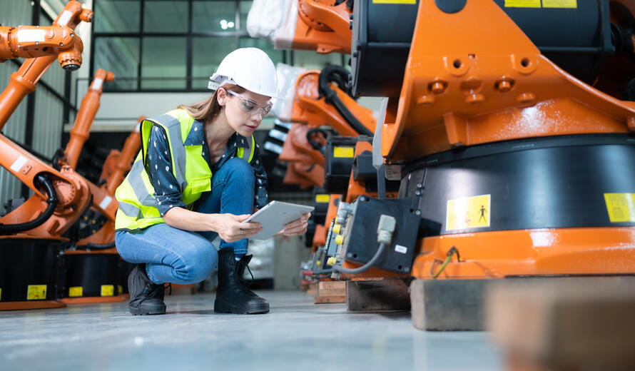 Female Technician Inspecting and repairing robotics arm in robots hangar and test the operation of the machine after being used for a while, as well as updating the software and calibration