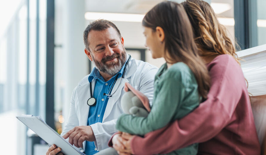 Doctor explaining test results, showing MRI scan to mother of young girl patient, delivering good news.