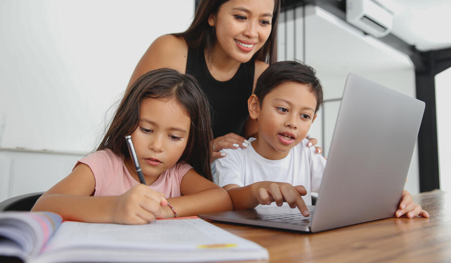 Close-up shot of Indonesian Mother Homeschooling Children at Home. Her daughter and son doing homework together in dining room.