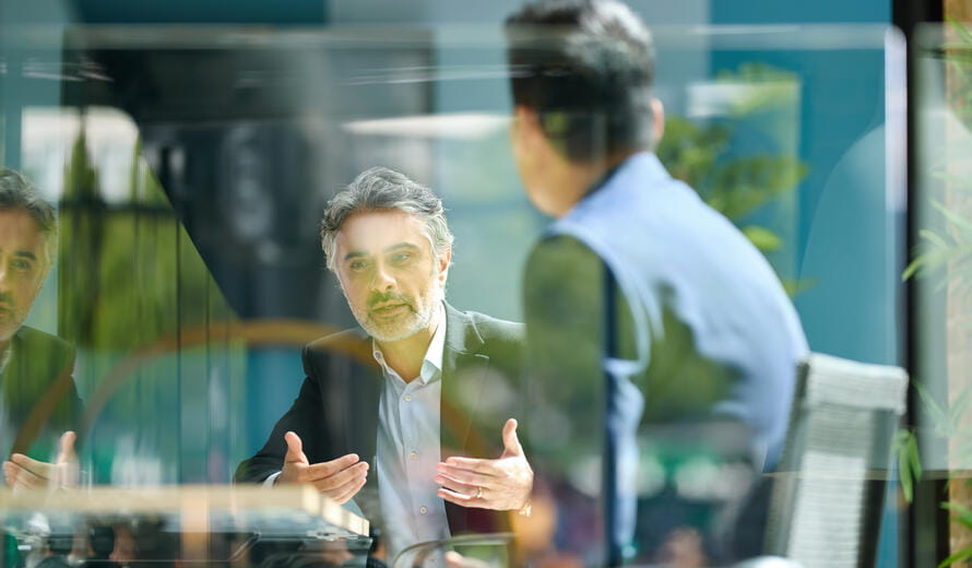 Mature businessman sitting on office balcony having meeting with colleague discussing project and gesturing, planning, togetherness, discussion