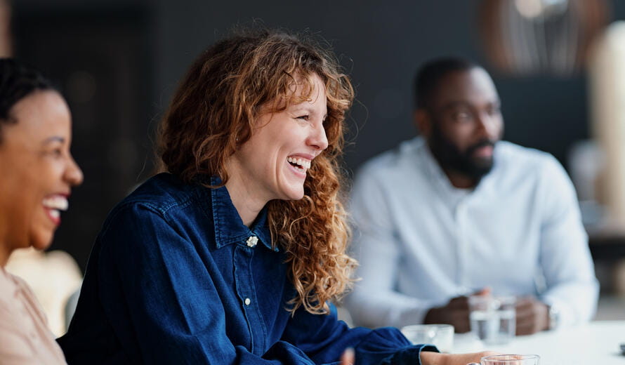 Three diverse professionals engaged in a lively discussion during a business meeting at a modern office.