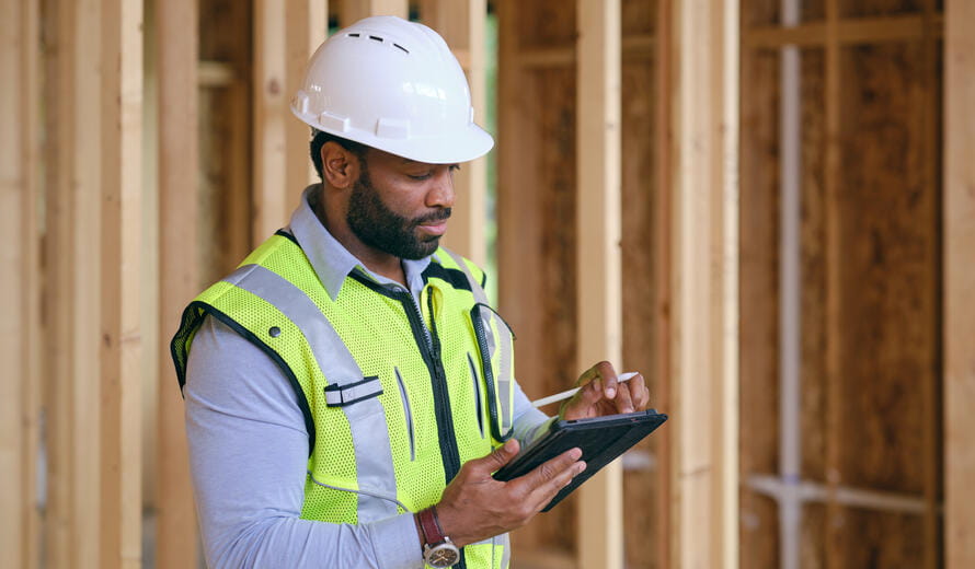 A construction worker inspecting a home under construction.