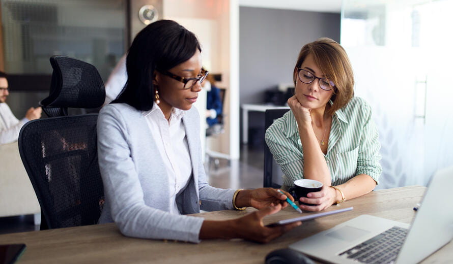 Image of two businesswomen analyzing graph with digital tablet in the office.