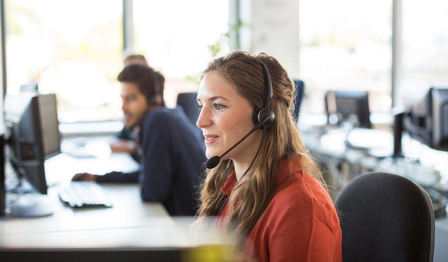 Smiling female customer representative wearing headphones working in office