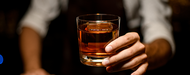 A bartender serving a glass of bourbon