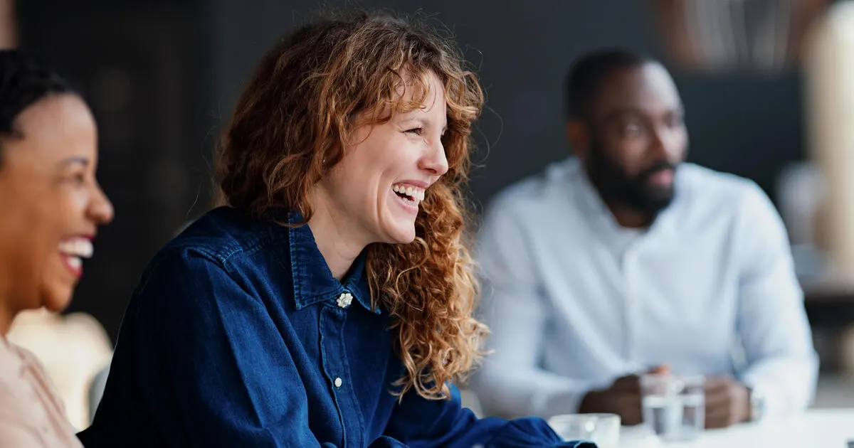 Three diverse professionals engaged in a lively discussion during a business meeting at a modern office.