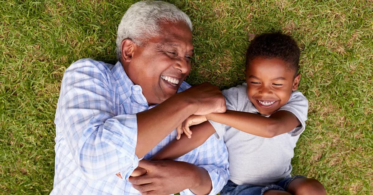 Grandfather and grandson play lying on grass, aerial view
