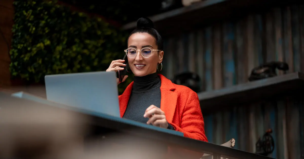 Happy and beautiful female freelancer working on her laptop in a high-end restaurant that she uses as an office space.